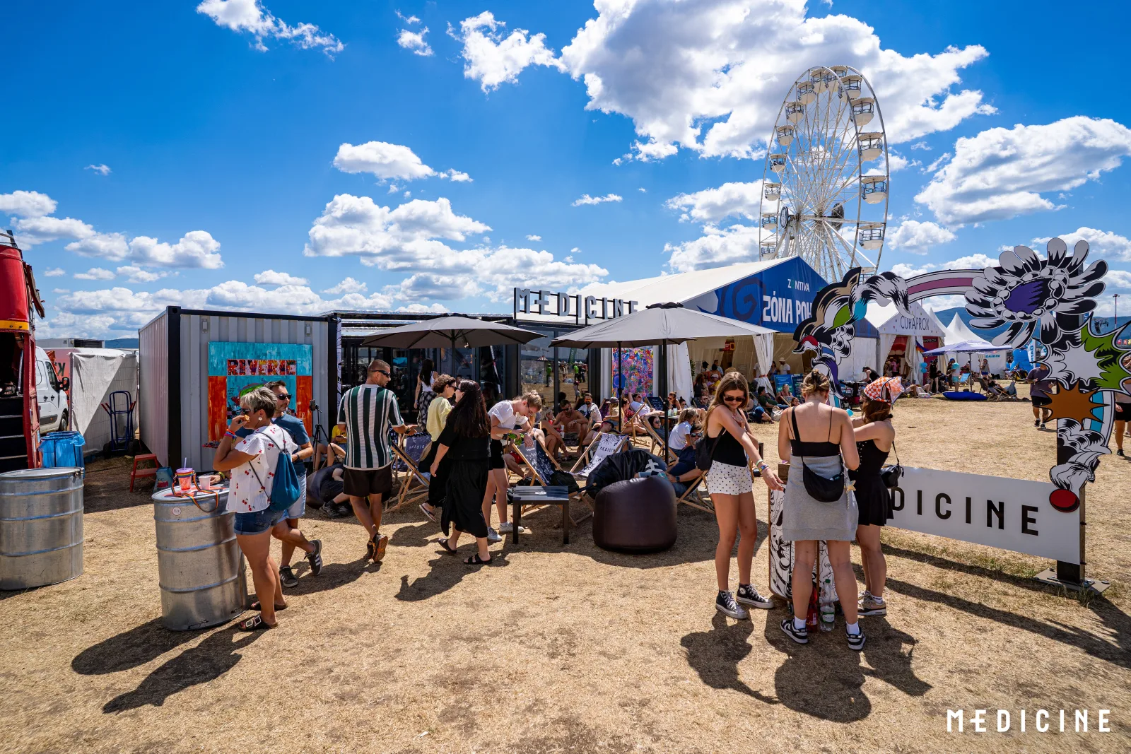 Chillout pred zónou Medicine na Pohode so slnečníkmi a ležadlami, v pozadí obrie festivalové koleso