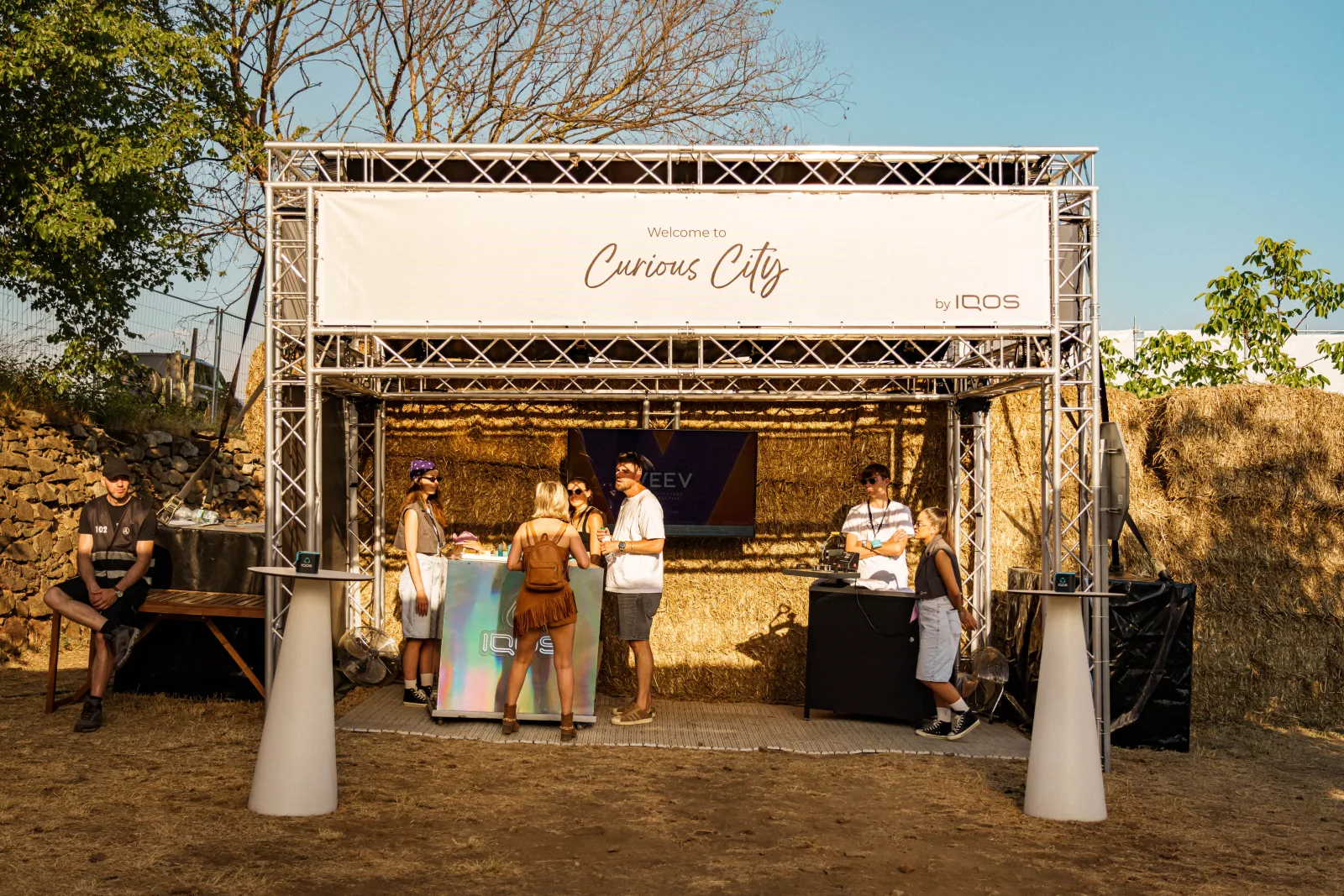 Vstupný pult zóny IQOS Curious City na Ženy Víno Funk s nápisom Welcome to Curious City a holografickým IQOS barom